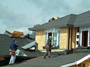 A home with a visible roof, attic venting, and mature trees in a quiet neighborhood after a seasonal change.