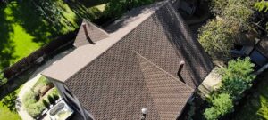 Homeowner comparing large roofing samples beside siding and trim outside a traditional house.
